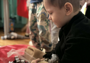 Chłopiec siedzi wśród ozdób choinkowych