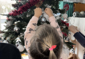 Dziewczynka zakłada bombkę na choinke