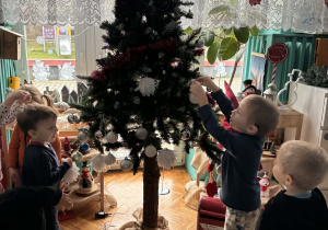 Dzieci zakładają bombki na choinkę