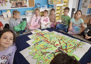Dzieci siedzą wokól choinki z puzzli