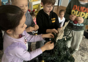 Grupa dzieci zakłada bombki choinkowe