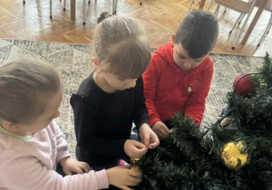 Dzieci ubierają choinkę w bombki