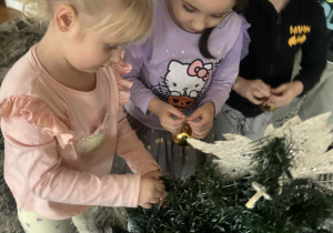 Dwie dziewczynki zakłądają bombki choinkowe na choinke