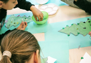 Dzieci naklejają cekiny na choinkę