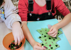 Dziewczynka układa cekiny na choince