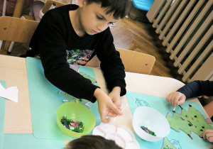 Chłopiec ozdabia choinkę cekinami