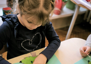 Dziewczynka przykleja cekiny na szablon choinki