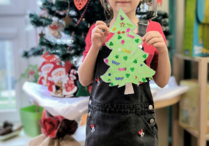 Dziewczynka stroi na tle ubranej choinki ze swojącekinową choinką