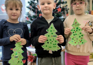 Troje dzieci ze swoimi cekinowymi choinkami
