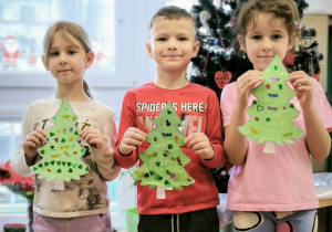 Dzieci na tle choinki z cekinowymi choinkami