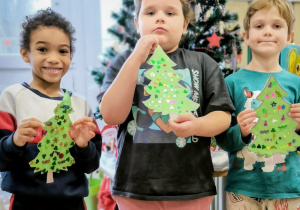 Dziewczynka i dwóch chłopców pokauje swoje cekinowe choinki