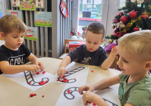 Chłopcy wyklejają cukrową laskę na czerwono