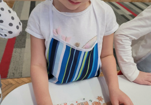 Dziewczynka dekoruje posypką pierniki