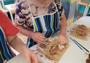 Dziewczynka układa białe dekoracje na piernikach