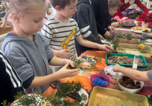 Dzieci przyklejaja gałązki na talerzyk