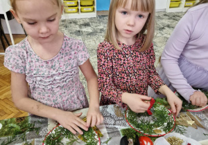 Dziewczynki doklejaja gałązki do talerzyka