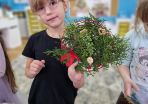 Dziewczynka pokazuje swój wieniec bozonarodzeniowy