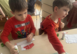 Chłopcy przyklejają czerwone kartoniki