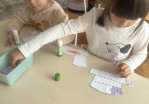 Dziewczynka przykleja fioletowe kartoniki