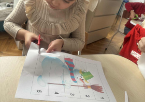 Dziewczynka przy stoliku wycina puzzle