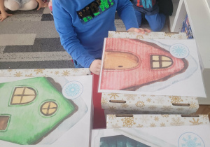 Chłopiec wrzuca znalezioną śnieżynkę do odpowiedniego domku