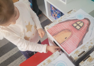 Dziewczynka wrzuca znalezioną śnieżynkę do odpowiedniego domku