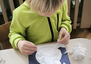 Chłopiec przykleja bibułę