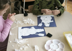 Dzieci przy stoliku robią kulki z bibuły