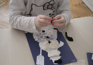 Dziewczynka robi czarne kulki z bibuły