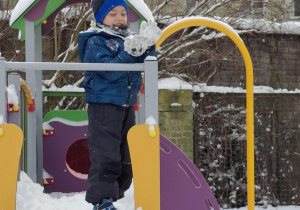 Chlopiec stoi w śniegu na domku