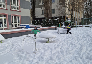 Dzieci biegają po śniegu na placu zabaw