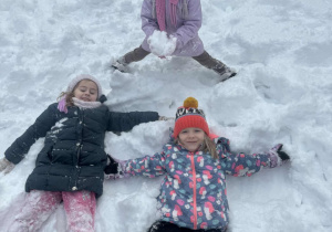 Dwie dziewczynki robią aniołki na śniegu