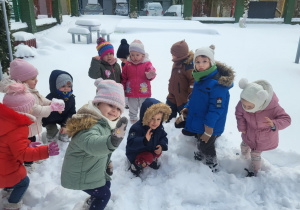 dzieci stoją na śnigu machając