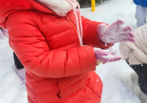 dziewczynka otrzepuje rękawiczki ze śniegu