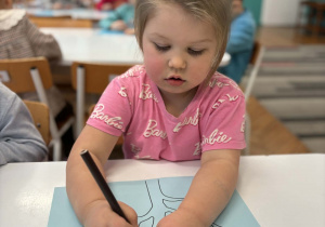 Dziewczynka koloruje drzewo na brązowo