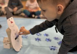 Chłopiec wrzuca śnieżynkę niebieską