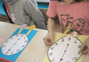 Dziewczynka nakleja na karton tarczę zegara