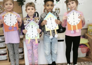 Dzieci na tle pór roku stoją z zegarami