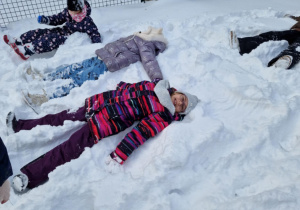 Dzieci robią aniołki na śniegu