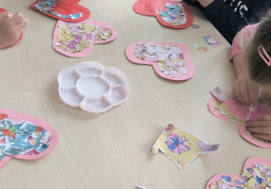 Dzieci siedza przy stole i drą kolorowe papiery