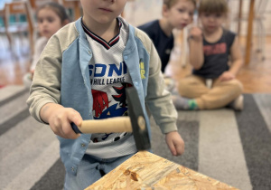 Chłopiec wbija gwóźdź młotkiem