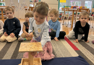 Dziewczynka wbija gwóźdź w podstawę karmnika