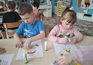 Dzieci wyklejają kolorowym papierem