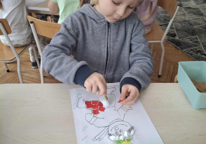 Chłopiec przykleja czerwone małe kartoniki