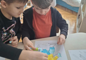 Chłopiec nakleja niebieskie kartoniki