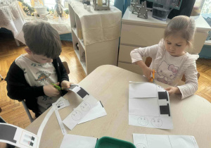 Dzieci przy stole wycinają nożyczkami