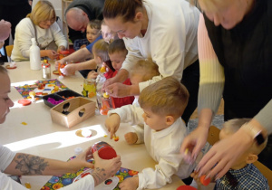 dziadkowie z wnuczkami ozdabiają lampiony zimowe