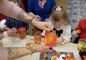 dziadkowie z wnuczkami ozdabiają lampiony zimowe