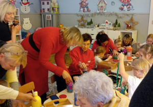 dziadkowie z wnuczkami ozdabiają lampiony zimowe