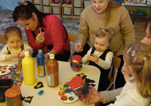 dziadkowie z wnuczkami ozdabiają lampiony zimowe